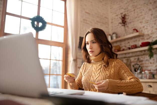 Foto vrouw die in sweater aan laptop werkt