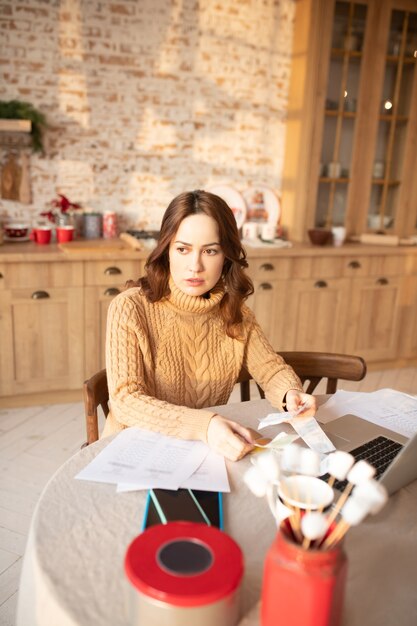 Vrouw die in sweater aan laptop werkt