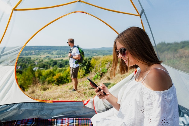 Vrouw die in tent haar telefoon bekijkt