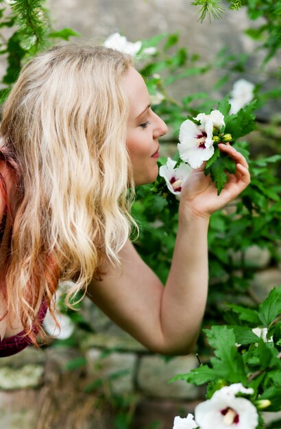 Vrouw die in tuin bij bloemen snuift