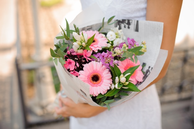 Vrouw die in witte kleding een mooi boeket van bloemen houdt