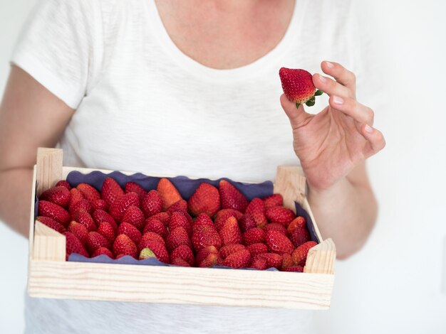 Vrouw die in witte t-shirt houten dooshoogtepunt van rijpe aardbeien houdt