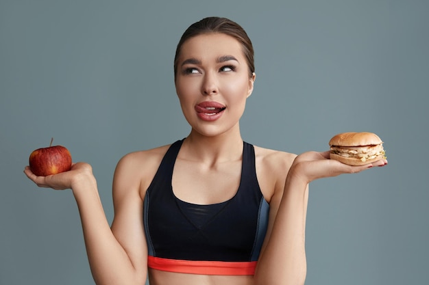 Vrouw die keuze maakt tussen appel en hamburger dieetconcept gezond eten