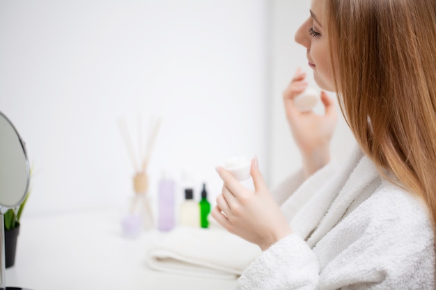 Vrouw die klaar voor het werk wordt dat ochtendmake-up in badkamerspiegel thuis doet.