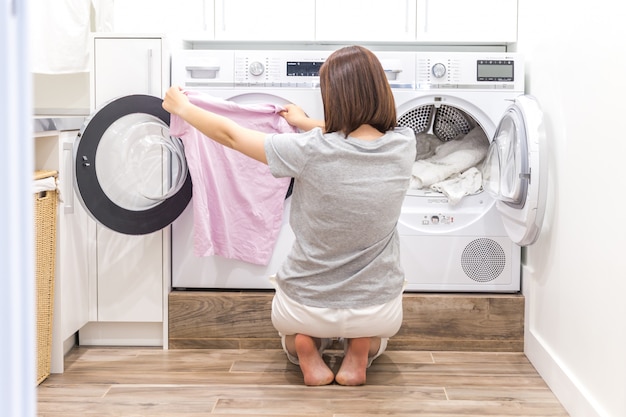 Vrouw die kleren zet aan wasmachine voor was