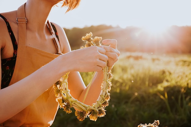 vrouw die krans van bloemen maakt paardebloemen op bloeiend veld Zomer levensstijl