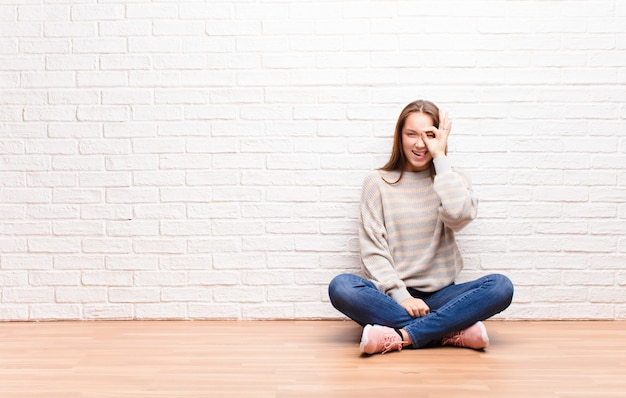 Foto vrouw die lacht vrolijk met grappig gezicht, een grapje maakt en door kijkgaatje kijkt, geheimen bespionerend