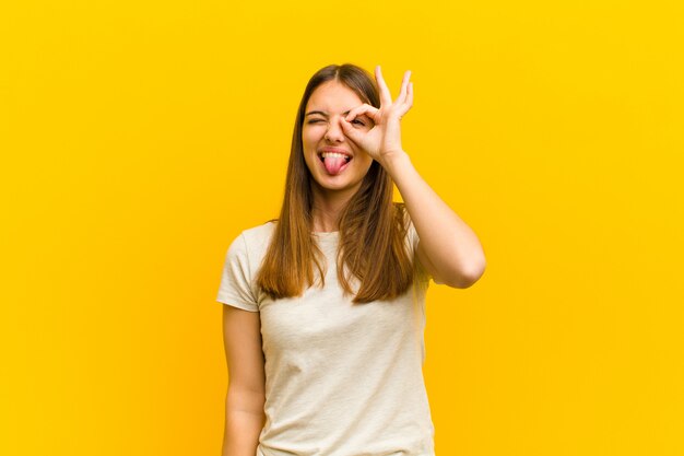 vrouw die lacht vrolijk met grappig gezicht, een grapje maakt en door kijkgaatje kijkt, geheimen bespionerend