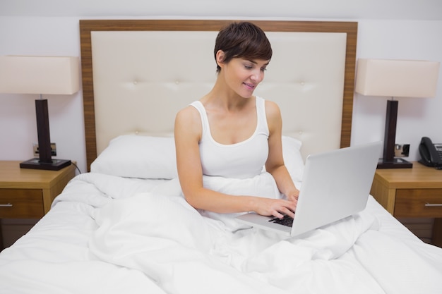 Vrouw die laptop in bed met behulp van