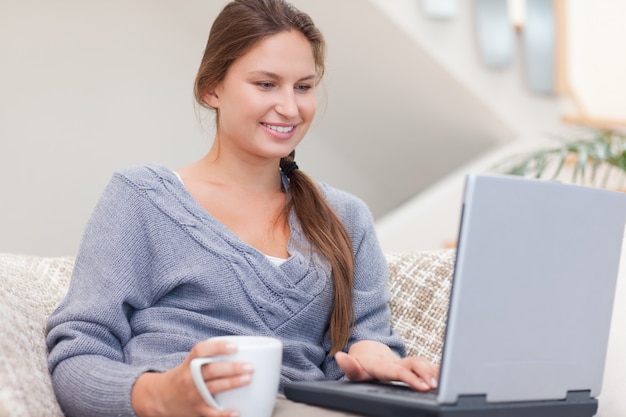 Vrouw die laptop met behulp van terwijl het hebben van een thee