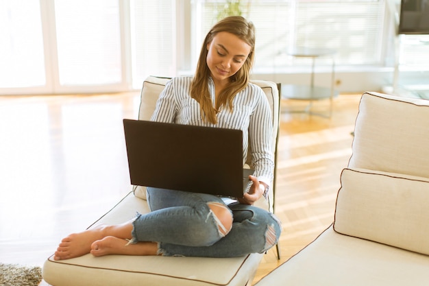 Vrouw die laptop met behulp van terwijl het ontspannen op de laag in de ruimte