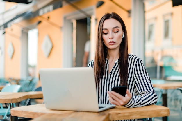 Vrouw die laptop zitting in koffie in openlucht gebruikt