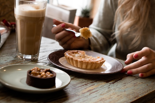 Vrouw die latte drinkt en cake eet in de coffeeshop