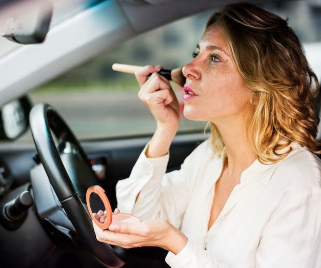 Vrouw die make-up in een auto draagt