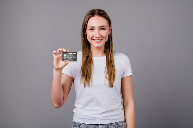 Vrouw die malplaatjecreditcard tonen en glimlachen geïsoleerd op grijs