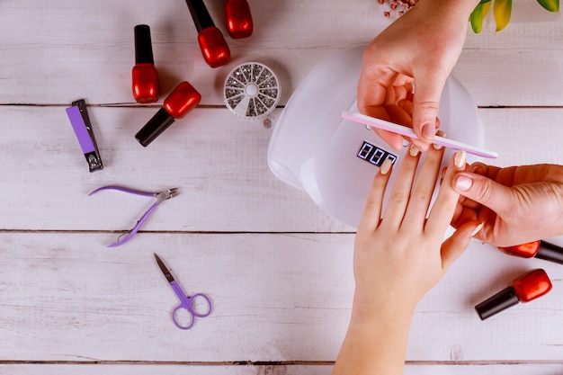 Vrouw die manicure met spijkerraad of nailfile maakt