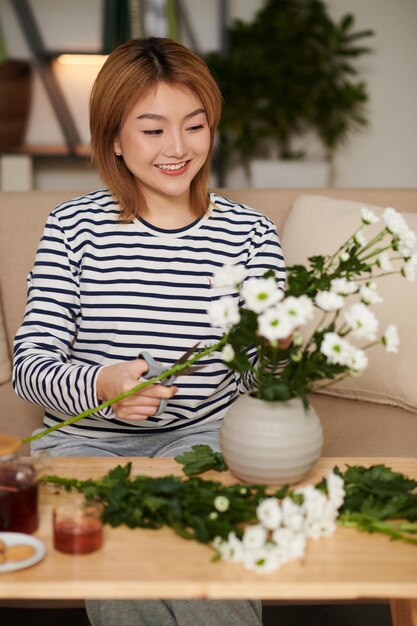 Vrouw die margrietbloemen snijdt