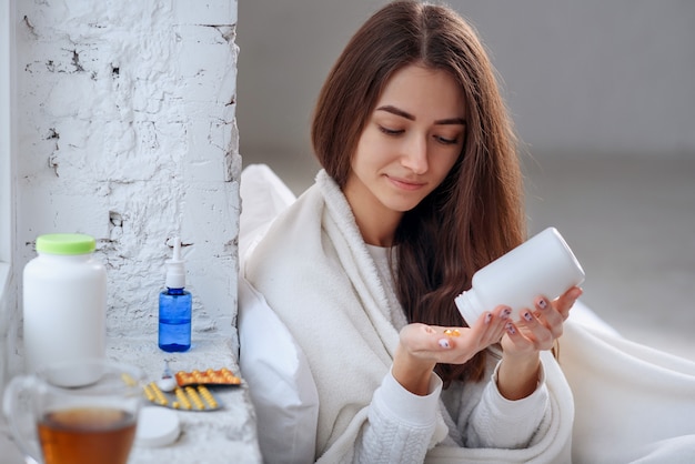 Vrouw die medicijn, tabletten en capsules bij de hand morst