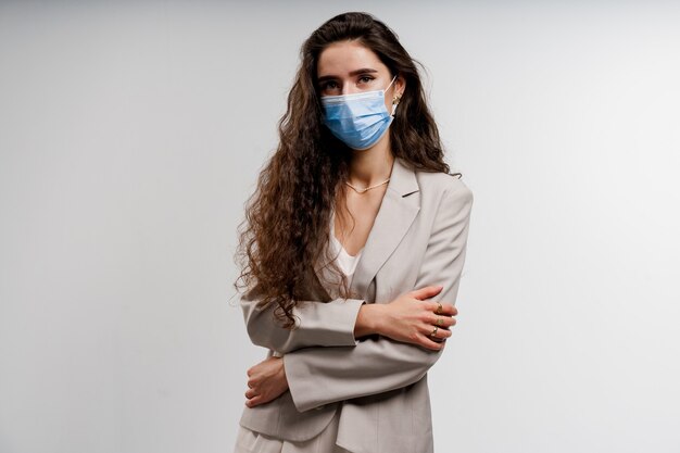 Vrouw die medisch masker draagt dat op witte achtergrond wordt geïsoleerd