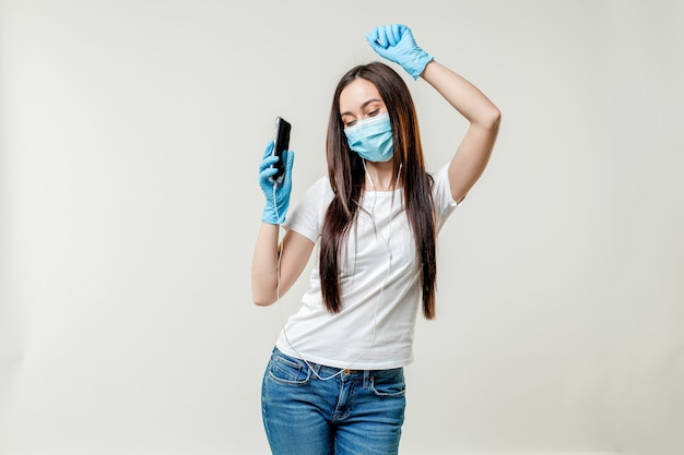 Foto vrouw die met earpods danst die masker en handschoenen draagt