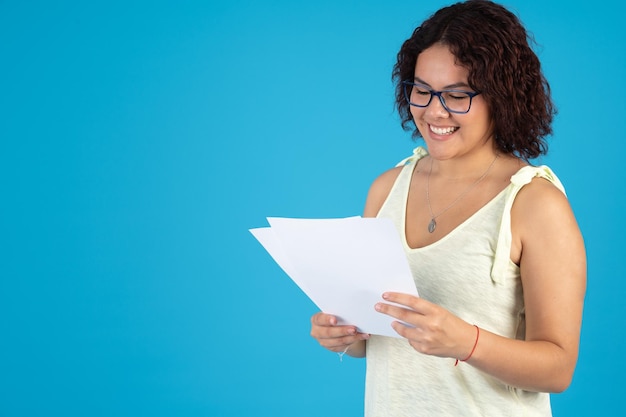 Vrouw die met een bril enkele documenten leest terwijl ze vrolijk glimlacht