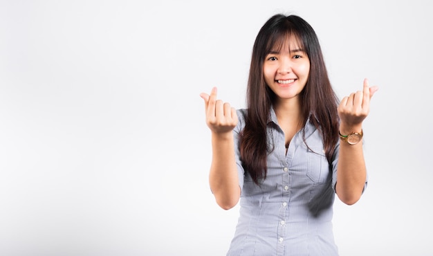 Vrouw die met haar glimlach staat en een minihartteken toont met haar vinger