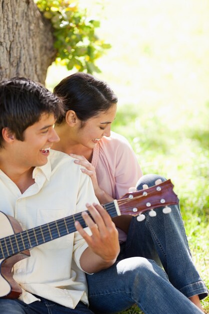 Vrouw die met haar vriend lachen die de gitaar speelt