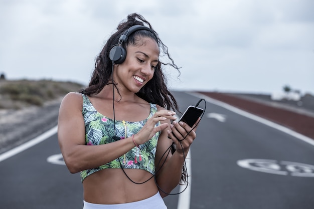 Vrouw die met hoofdtelefoons aan muziek met slimme telefoon luistert