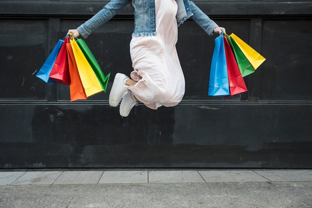 Foto vrouw die met kleurrijke het winkelen pakketten springt