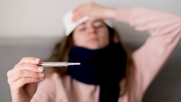 Foto vrouw die met koorts haar temperatuur controleert