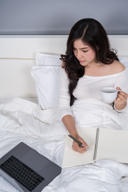 Vrouw die met laptop computer aan bed werkt