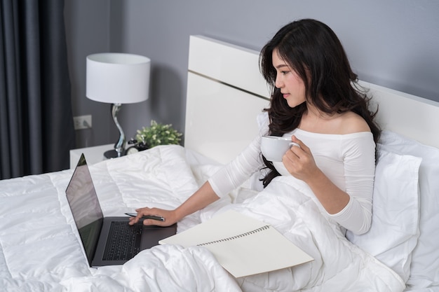 Vrouw die met laptop computer aan bed werkt