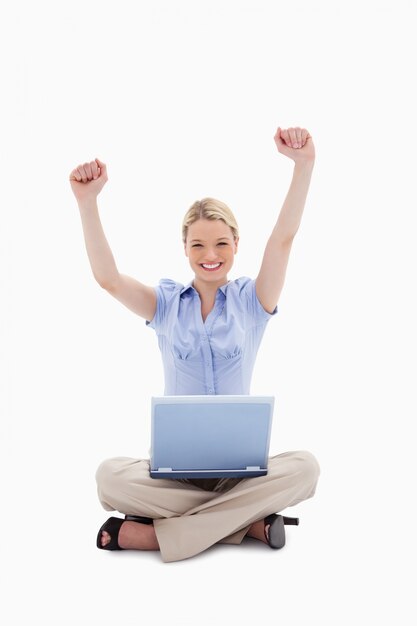 Vrouw die met laptop haar handen opheft