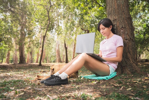 Vrouw die met laptop notitieboekje in bos werkt