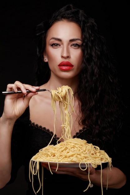 Vrouw die met rode lippen spaghetti eet