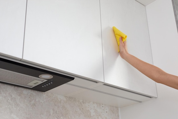 Vrouw die meubels in de keuken met de hand schoonmaakt met een vod of doek