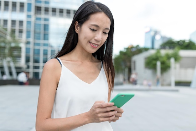 Vrouw die mobiel in de stad controleert