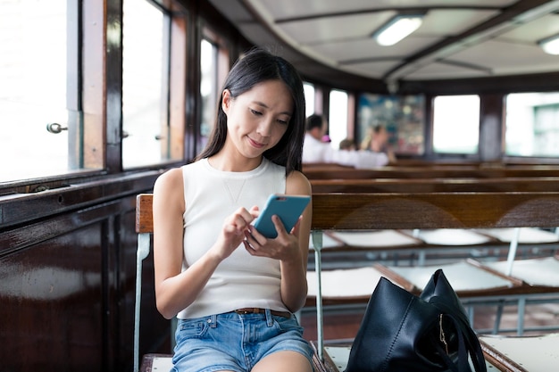 Vrouw die mobiele telefoon gebruikt en veerboot neemt in Hong Kong