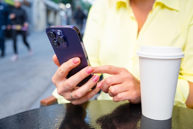 Vrouw die mobiele telefoon gebruikt terwijl ze in het openluchtcafé zit