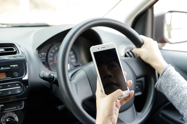 Vrouw die mobiele telefoon houdt die een tekst verzendt terwijl het drijven van een auto.