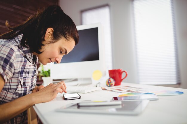 Vrouw die mobiele telefoon in bureau met behulp van