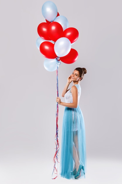 Vrouw die mooie kleding met heel wat kleurrijke ballons draagt