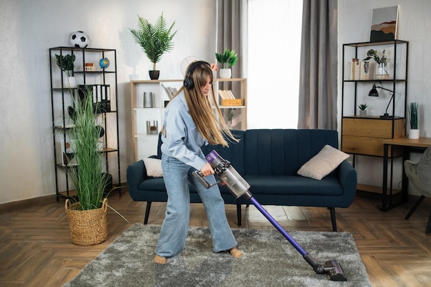 Vrouw die muziek luistert tijdens het schoonmaken van huis met vacuüm