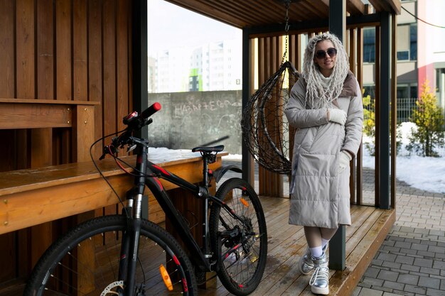 Vrouw die naast de fiets op de veranda staat