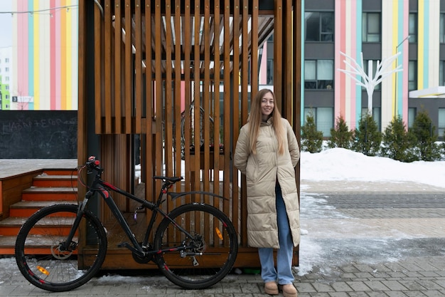 Vrouw die naast de fiets staat voor het gebouw