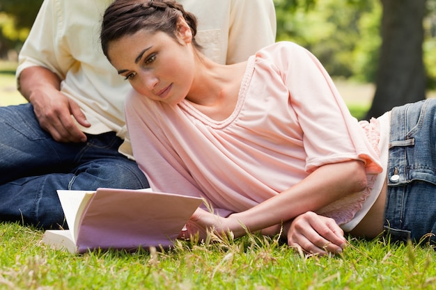 Vrouw die naast haar vriend ligt terwijl het lezen van een boek