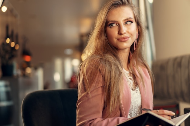 Vrouw die nota's maakt terwijl het zitten in een koffiewinkel