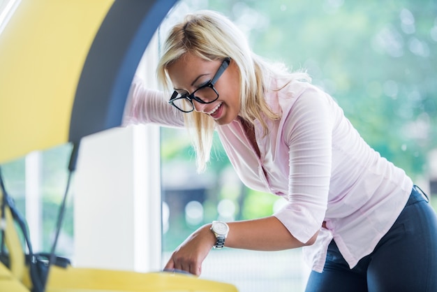 Vrouw die onder autokap kijkt