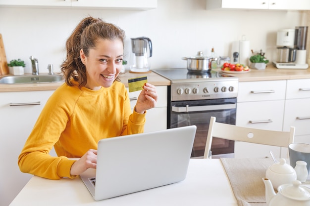 Vrouw die online winkelt en met gouden creditcard betaalt