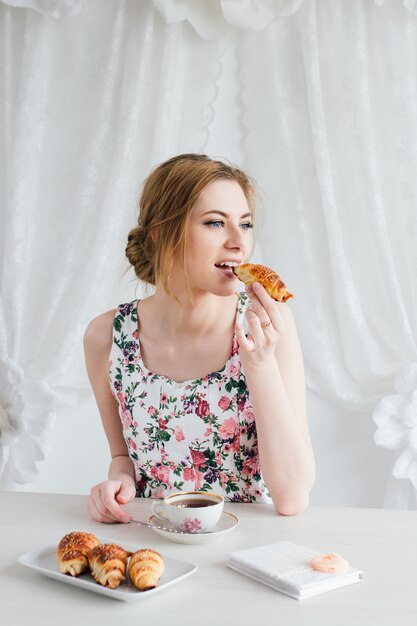 Vrouw die Ontbijt met eigengemaakte thee en verse croissants heeft